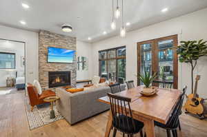 Dining area with a stone fireplace and light wood-type flooring