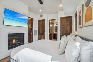 Bedroom with electric panel, ensuite bath, wood-type flooring, and ceiling fan