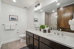 Bathroom with toilet, tile patterned floors, and double vanity