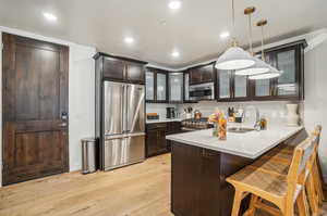 Kitchen featuring a kitchen bar, light hardwood / wood-style flooring, sink, kitchen peninsula, and premium appliances