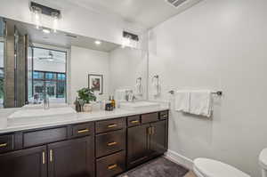 Bathroom featuring toilet and dual bowl vanity