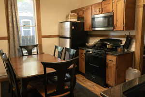 Kitchen featuring dark stone counters, stainless steel appliances, and light hardwood / wood-style floors