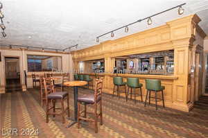 Dining room featuring a textured ceiling, bar, and track lighting