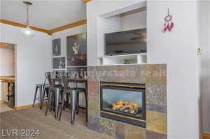 Kitchen featuring crown molding, decorative light fixtures, and a tile fireplace