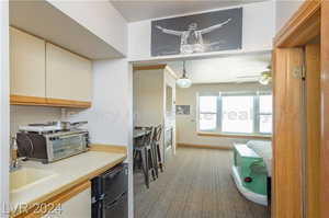 Kitchen with white cabinets, sink, pendant lighting, light colored carpet, and ceiling fan