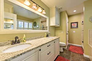 Bathroom with walk in shower, tile patterned flooring, toilet, and double sink vanity