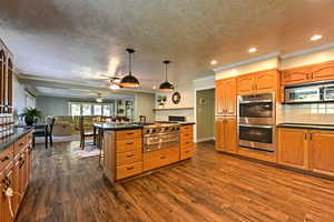 Kitchen featuring ceiling fan, stainless steel appliances, crown molding, a center island, and dark hardwood / wood-style floors