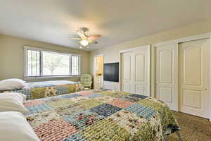 Carpeted bedroom with multiple closets and ceiling fan