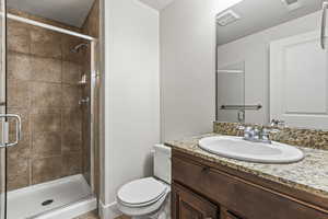 Bathroom featuring a shower with shower door, toilet, and vanity