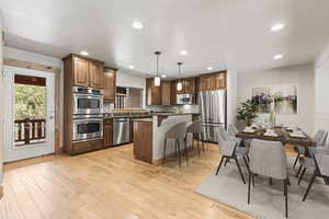 Kitchen featuring a breakfast bar, hanging light fixtures, light hardwood / wood-style flooring, a kitchen island, and stainless steel appliances