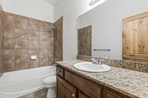 Full bathroom featuring tile patterned flooring, toilet, vanity, and tiled shower / bath