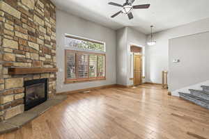 Living room with a fireplace, light hardwood / wood-style flooring, and ceiling fan