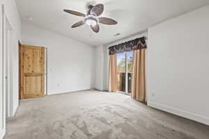 Carpeted empty room with ceiling fan and vaulted ceiling