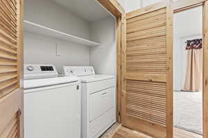 Laundry room with light colored carpet and independent washer and dryer