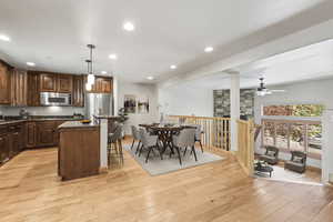 Kitchen with a center island, dark stone countertops, light hardwood / wood-style flooring, ceiling fan, and stainless steel appliances