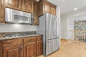 Kitchen featuring dark stone countertops, stainless steel appliances, and light hardwood / wood-style floors