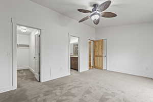 Unfurnished bedroom with a closet, a spacious closet, connected bathroom, ceiling fan, and light colored carpet