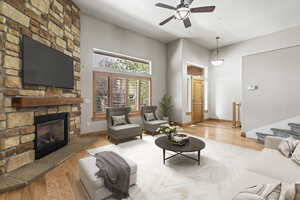 Living room with ceiling fan, light hardwood / wood-style flooring, and a stone fireplace