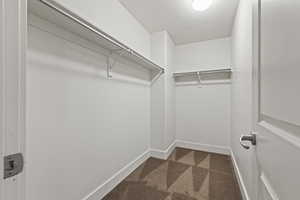 Walk in closet with dark colored carpet