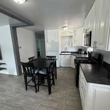 Kitchen featuring light tile patterned floors, white cabinetry, black appliances, and sink