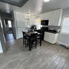 Kitchen featuring white cabinetry, black appliances, sink, and light wood-type flooring