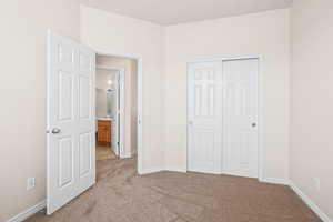 Unfurnished bedroom with light carpet and a closet