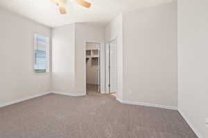 Unfurnished bedroom featuring a closet, light carpet, a spacious closet, and ceiling fan