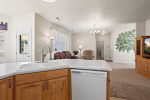 Kitchen with a notable chandelier, light carpet, dishwasher, and sink