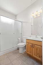 Bathroom featuring tile patterned flooring, a shower with door, toilet, and vanity