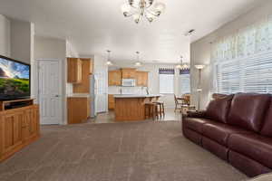 Living room with light carpet, a notable chandelier, sink, and a textured ceiling