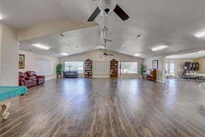 Unfurnished living room with a textured ceiling, lofted ceiling, ceiling fan, and hardwood / wood-style floors