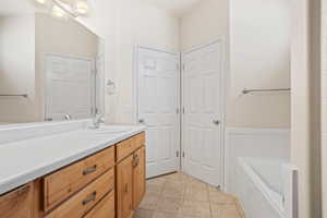 Bathroom featuring tile patterned floors, a tub to relax in, and vanity