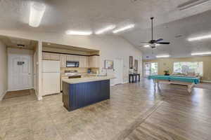 Kitchen featuring white refrigerator, ceiling fan, sink, stove, and pool table