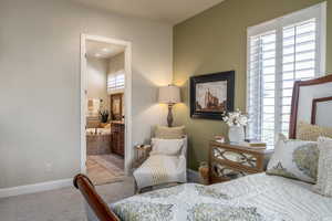 Bedroom featuring ensuite bathroom and carpet flooring