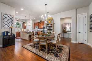 Dining area featuring dark wood-type flooring, sink, and a chandelier