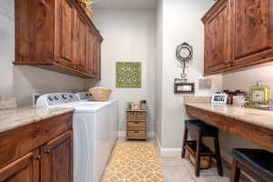 Clothes washing area with cabinets, washing machine and dryer, and light tile patterned floors