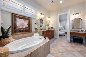 Bathroom with tiled tub, vanity, and tile patterned floors