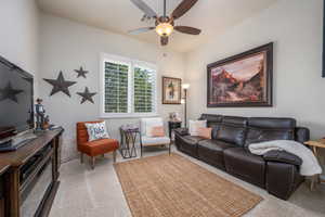 Carpeted living room featuring ceiling fan