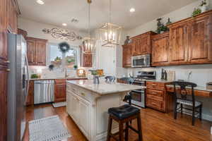 Kitchen featuring a breakfast bar, light stone counters, a kitchen island, dark hardwood / wood-style floors, and appliances with stainless steel finishes