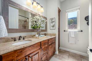 Bathroom with tiled shower, tile patterned flooring, and dual bowl vanity