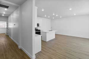 Interior space with sink, light hardwood / wood-style flooring, stainless steel appliances, and a center island with sink