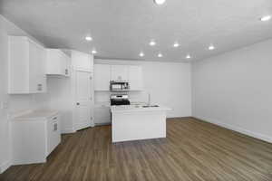 Kitchen featuring stove, a center island with sink, hardwood / wood-style floors, sink, and white cabinetry