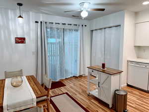 Kitchen with light hardwood / wood-style floors, white dishwasher, ceiling fan, and hanging light fixtures