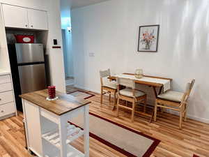 Kitchen featuring stainless steel fridge, light hardwood / wood-style flooring, and white cabinets