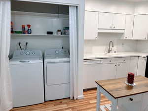 Laundry room with sink, light hardwood / wood-style flooring, and washing machine and dryer