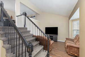 Staircase with dark hardwood / wood-style floors and vaulted ceiling