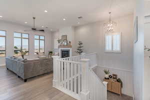 Living room featuring light hardwood / wood-style flooring, a healthy amount of sunlight, and ceiling fan with notable chandelier