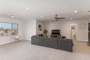 Carpeted living room featuring ceiling fan