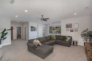 Carpeted living room featuring ceiling fan