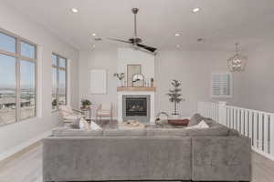 Living room with light hardwood / wood-style flooring and ceiling fan with notable chandelier